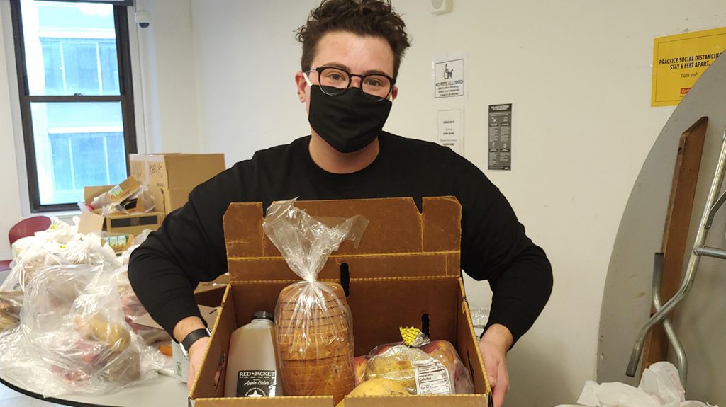 News 16 GMHC staff member preparing a box meal for an agency client.